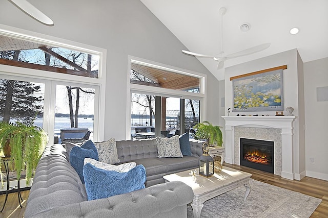 living room with hardwood / wood-style flooring, a water view, high vaulted ceiling, and ceiling fan