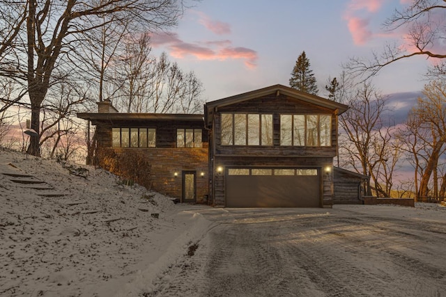 view of front of property with driveway, a chimney, and an attached garage