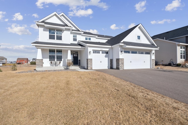 view of front of property featuring a porch, an attached garage, driveway, board and batten siding, and a front yard