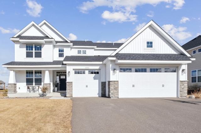 view of front of house featuring driveway, a porch, a garage, stone siding, and board and batten siding