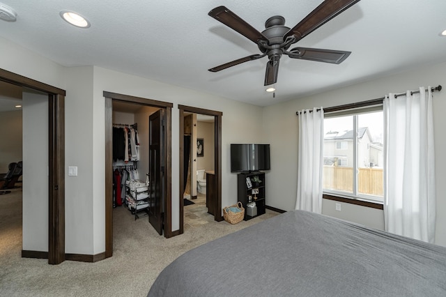 carpeted bedroom with ceiling fan, a walk in closet, ensuite bathroom, and a closet