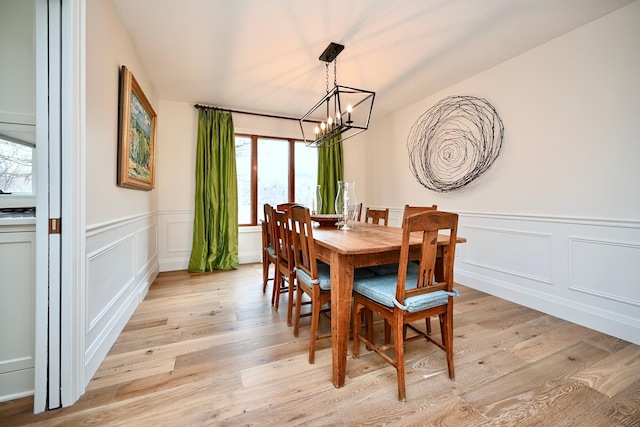 dining room featuring a notable chandelier, vaulted ceiling, and light wood-type flooring