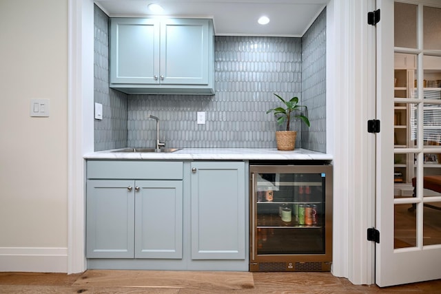 bar featuring wine cooler, sink, and decorative backsplash