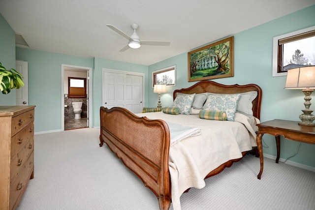 bedroom with ensuite bathroom, multiple windows, ceiling fan, light carpet, and a closet