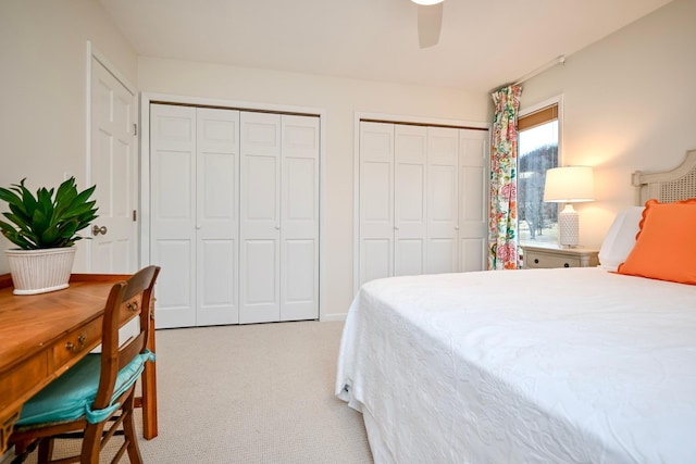 bedroom with two closets, light colored carpet, and ceiling fan