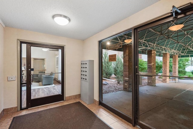 doorway to outside with tile patterned flooring, a textured ceiling, and baseboards