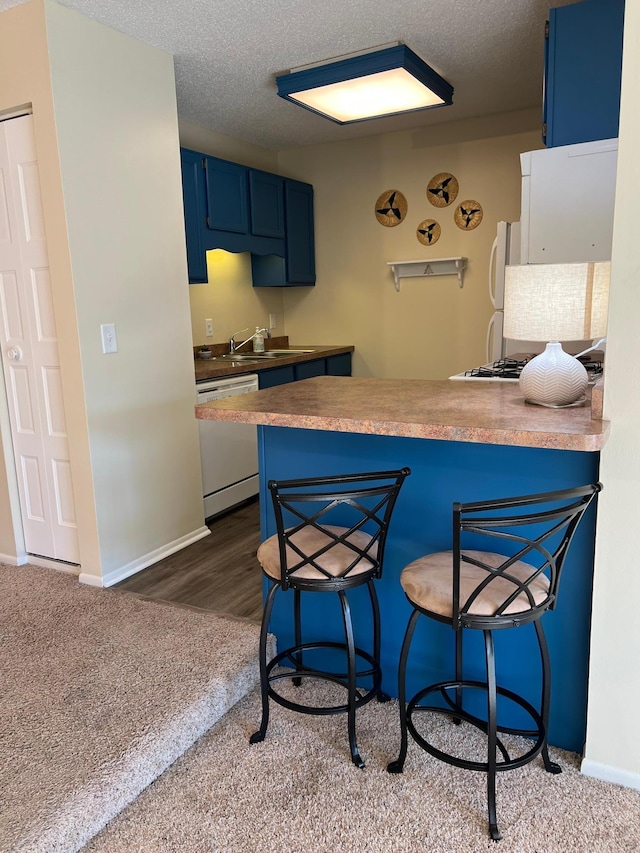 kitchen with a peninsula, blue cabinetry, a breakfast bar, and white appliances