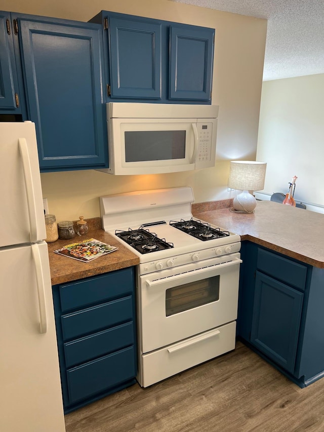 kitchen featuring blue cabinets, white appliances, and a peninsula