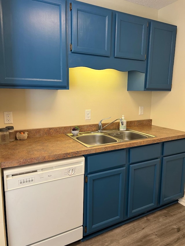 kitchen with dishwasher, blue cabinetry, dark wood-type flooring, and a sink