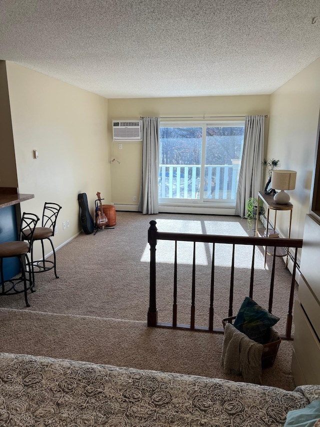 interior space with a textured ceiling, a wall mounted AC, carpet, and baseboards