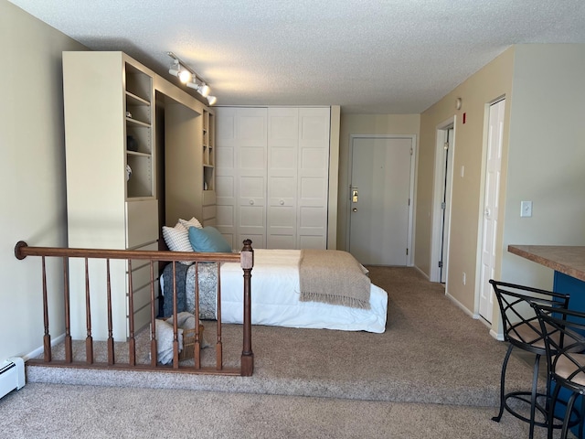 bedroom with carpet floors, a baseboard radiator, a closet, a textured ceiling, and baseboards