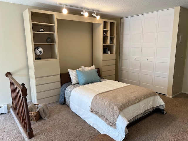 carpeted bedroom with rail lighting, a baseboard radiator, a closet, and a textured ceiling