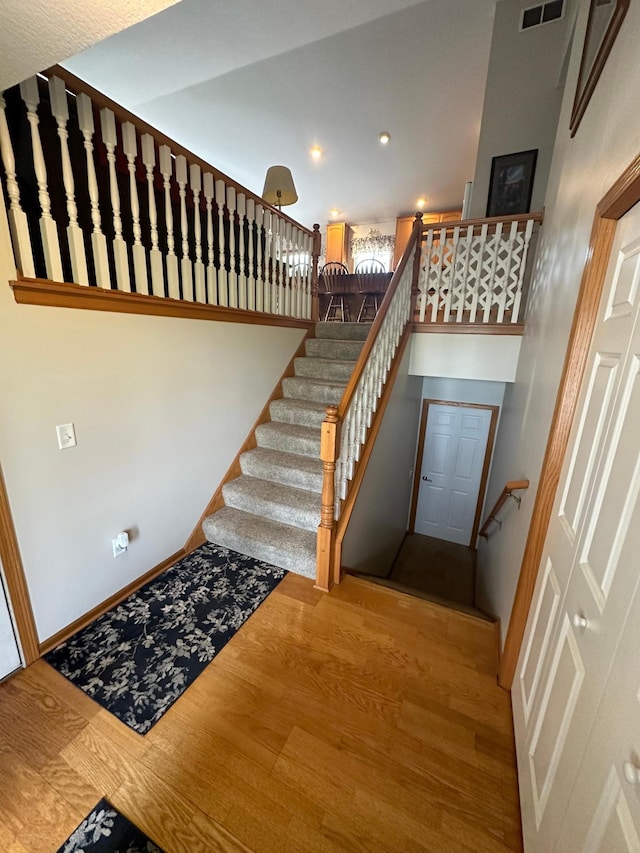 stairs with hardwood / wood-style floors and a towering ceiling