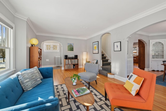 living room with baseboards, arched walkways, wood finished floors, stairs, and crown molding