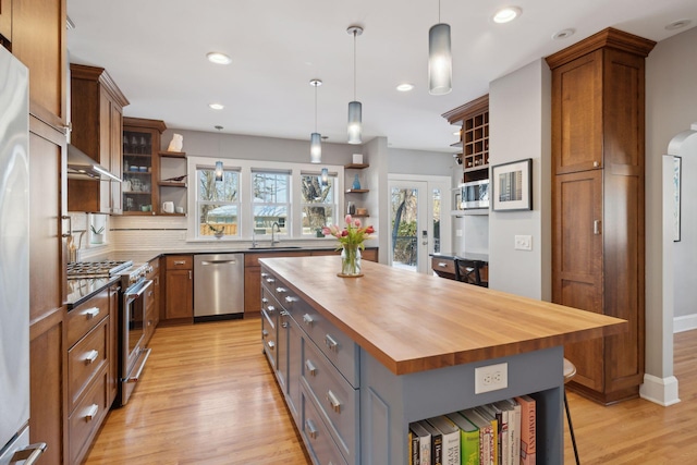 kitchen with open shelves, butcher block countertops, a kitchen island, and glass insert cabinets