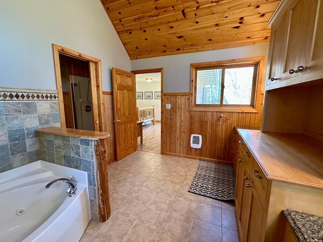14788 Coyote Dr, Park Rapids, MN 56470 - bathroom with wainscoting, wood ceiling, a whirlpool tub, vaulted ceiling, and tile patterned floors
