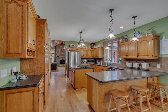 kitchen with pendant lighting, backsplash, a kitchen breakfast bar, kitchen peninsula, and stainless steel appliances