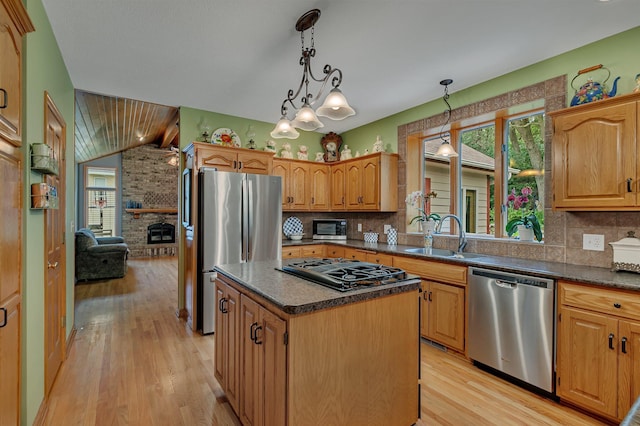 kitchen with dark countertops, light wood-style flooring, a sink, and appliances with stainless steel finishes