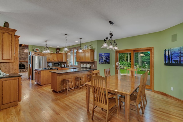 dining room with a textured ceiling, light wood finished floors, and baseboards