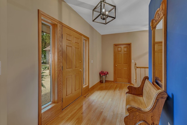 foyer entrance with a chandelier, light wood-type flooring, and baseboards