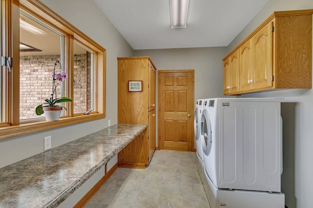 laundry area featuring washer and dryer, cabinet space, and a textured ceiling