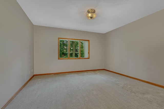 unfurnished room with light colored carpet and baseboards