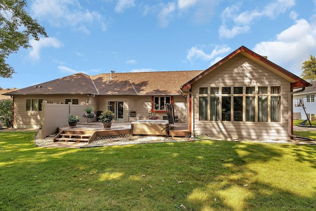 back of house featuring a yard, a shingled roof, a hot tub, and a deck