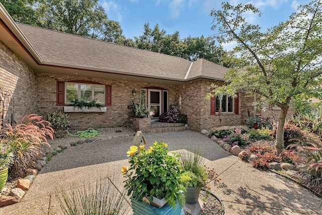 ranch-style home featuring brick siding and roof with shingles