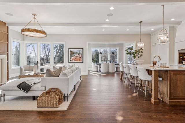 living room featuring beamed ceiling, dark hardwood / wood-style floors, sink, and a wealth of natural light