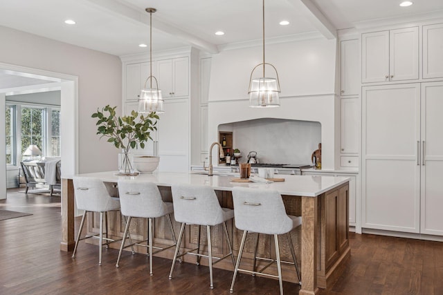 kitchen with beamed ceiling, white cabinetry, pendant lighting, and a spacious island
