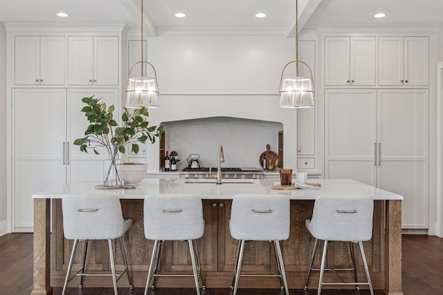 kitchen with hanging light fixtures, sink, a center island with sink, and white cabinets