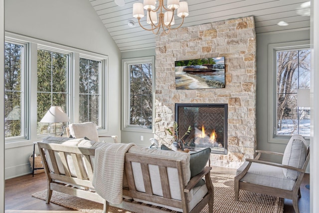 sunroom featuring lofted ceiling, wood ceiling, a stone fireplace, and a wealth of natural light