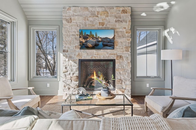 living room with a fireplace, a wealth of natural light, vaulted ceiling, and hardwood / wood-style flooring