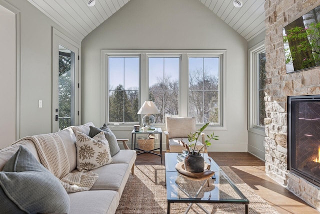 sunroom featuring vaulted ceiling, a stone fireplace, and wood ceiling