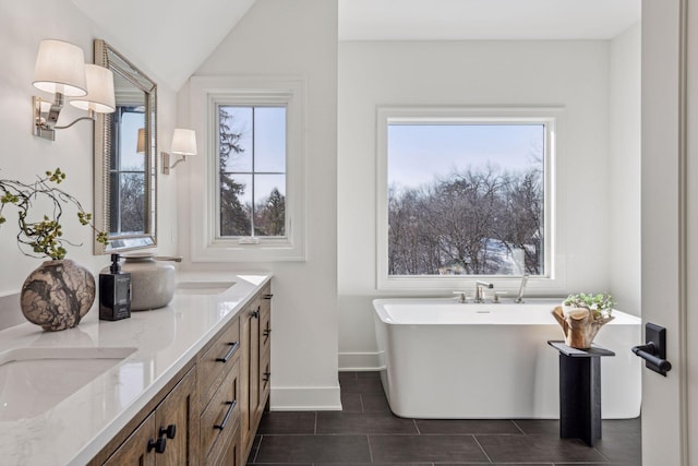 bathroom with vanity, vaulted ceiling, and a tub