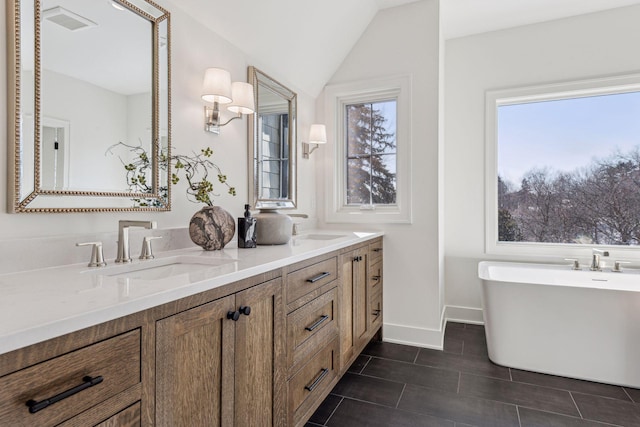 bathroom featuring vanity, a tub, lofted ceiling, and tile patterned floors