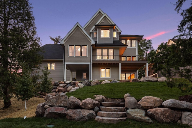 back house at dusk featuring a wooden deck and a yard