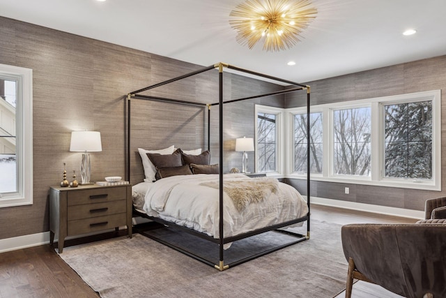 bedroom featuring multiple windows, hardwood / wood-style floors, and a notable chandelier