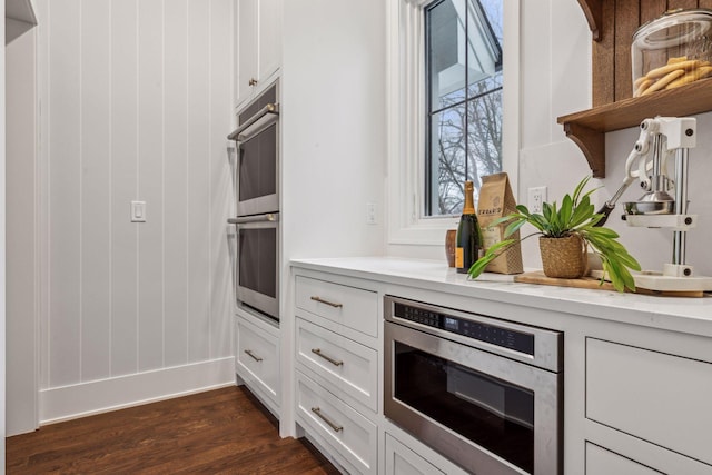 kitchen featuring white cabinetry, stainless steel appliances, and dark wood-type flooring