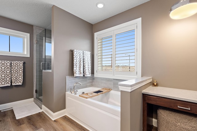 bathroom featuring wood-type flooring, shower with separate bathtub, and a textured ceiling