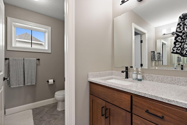 bathroom featuring vanity, toilet, and a textured ceiling