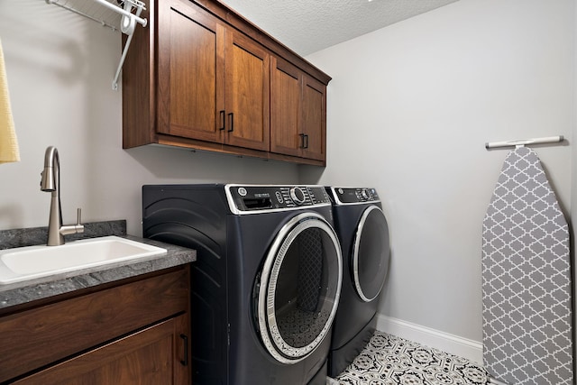 laundry area with sink, cabinets, light tile patterned floors, independent washer and dryer, and a textured ceiling