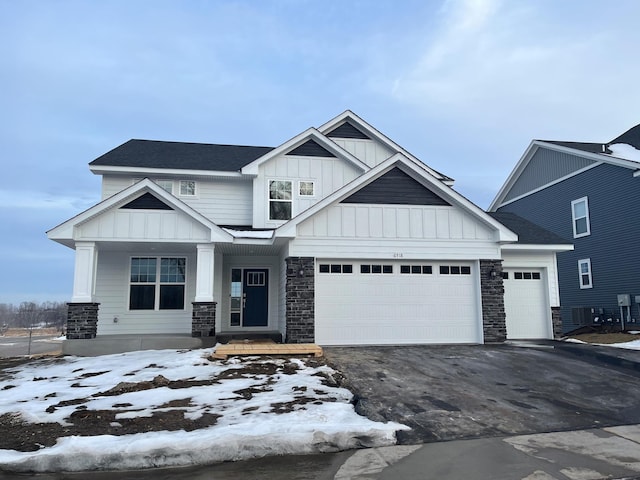 view of front of house with board and batten siding, stone siding, driveway, and an attached garage