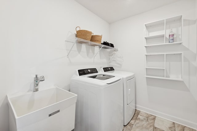 laundry area with laundry area, washer and dryer, baseboards, and a sink