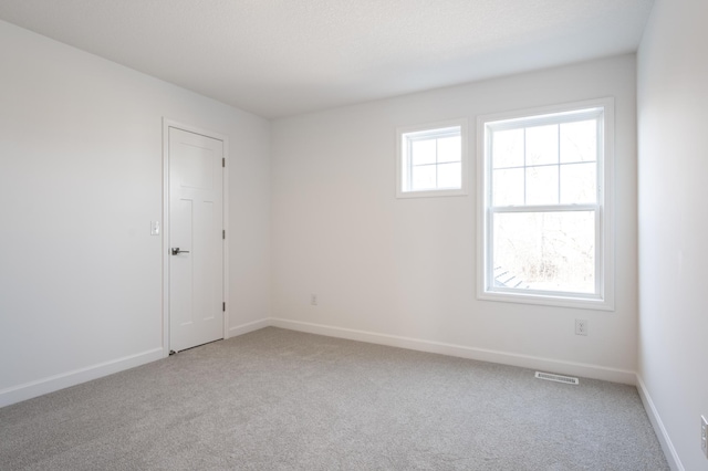 spare room with visible vents, carpet flooring, and baseboards