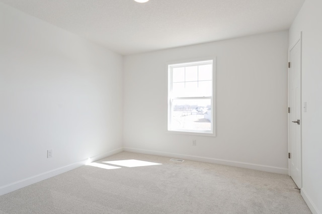 carpeted spare room featuring visible vents and baseboards