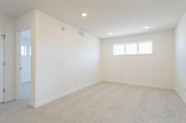 spare room featuring recessed lighting, light colored carpet, visible vents, and baseboards