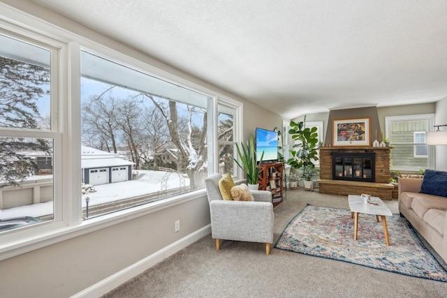 carpeted living room featuring a glass covered fireplace, a textured ceiling, and baseboards