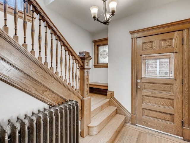 entrance foyer with an inviting chandelier, radiator heating unit, and light hardwood / wood-style flooring