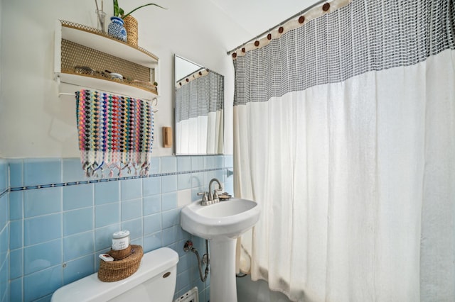 bathroom featuring curtained shower, wainscoting, tile walls, and toilet